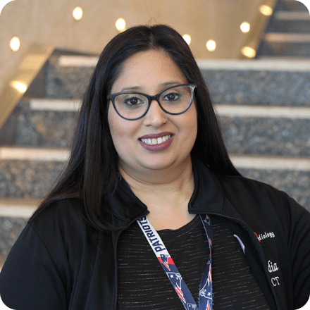 Nadia, a cardiology technologist, stands in front of a staircase
