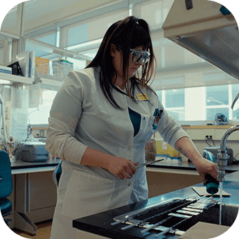 Stephanie in a white coat in the lab with rounder corners