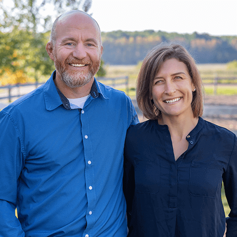 Jenny and Neil posed smiling at the camera in blue button up shirts