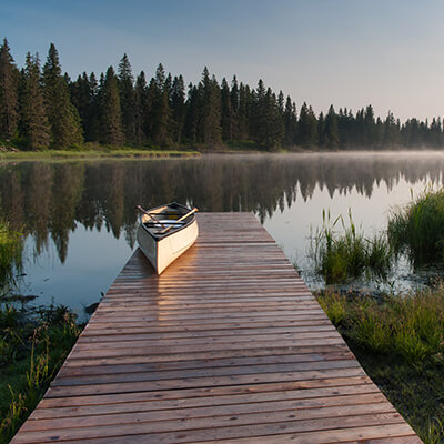 Canoe On A Dock At A Lake During A Misty Sunrise.